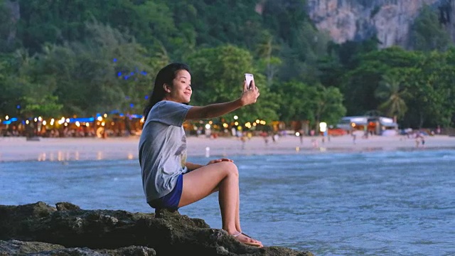 亚洲年轻女子在海滩上拿着手机视频素材