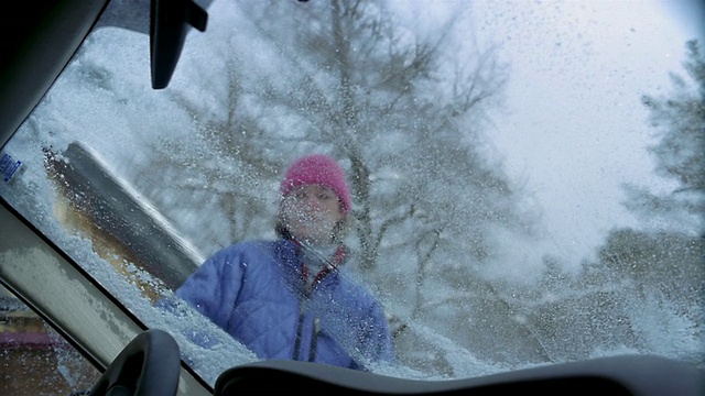 低角度中拍摄汽车视角的女人刷掉挡风玻璃上的雪/刮/佛蒙特视频素材