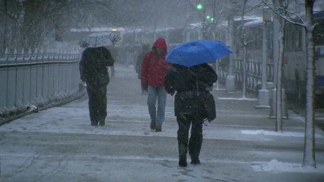 广角镜头下的行人在伞下走在人行道上的雪天/纽约市视频素材