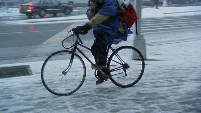 广角镜头自行车信使或快递员在人行道上骑自行车在下雪天/纽约市视频素材