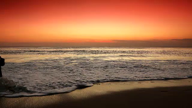 热带海滩上的日落，一个女人在用智能手机走路视频素材