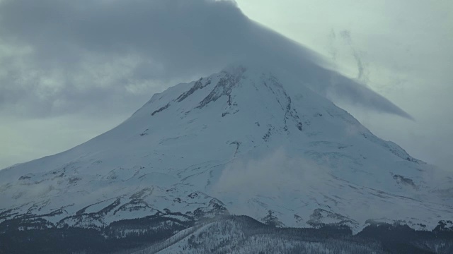 胡德山在冬季积雪覆盖的山峦和森林里，黄昏日落时遥拍近山顶吹雪视频素材