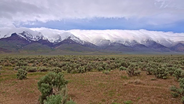 白雪皑皑的沙漠山脉和白云从阿尔沃德沙漠和山艾树春季斯滕斯山视频素材