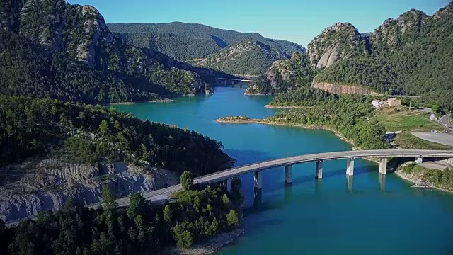 飞过美丽的绿松石湖在山上和几个桥横跨湖。视频素材