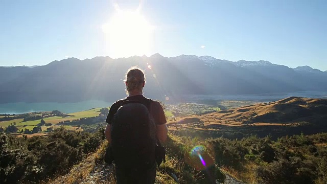 年轻的男性徒步旅行者走到草地上欣赏山景视频素材