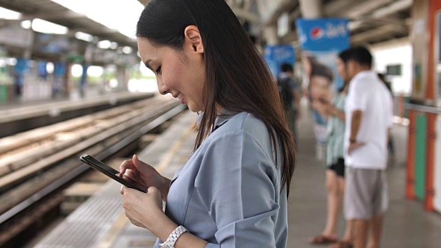 一名女子在火车站用智能手机进行社交视频素材