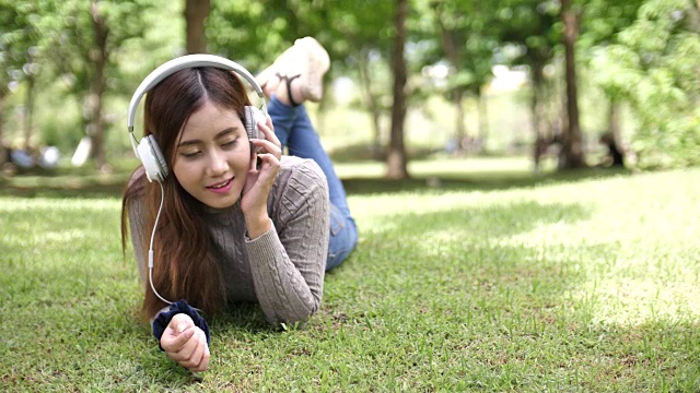 女人戴着耳机在公园里听音乐视频素材