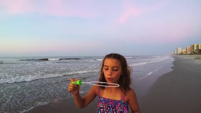 女孩在海滩上吹泡泡视频素材