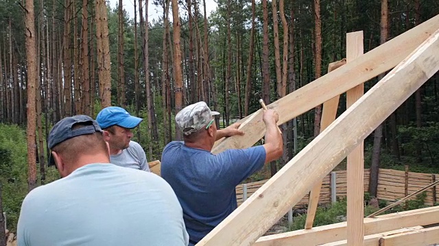 屋顶工人在屋顶上工作。建筑工人用锤子锤钉子。视频下载