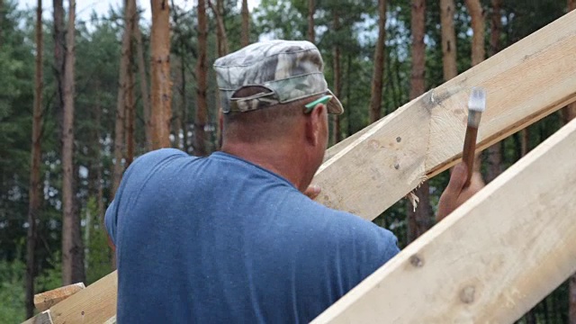 屋顶工人在屋顶上工作。建筑工人用锤子锤钉子。视频素材