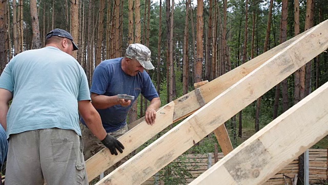 屋顶工人在屋顶上工作。建筑工人用锤子锤钉子。视频下载