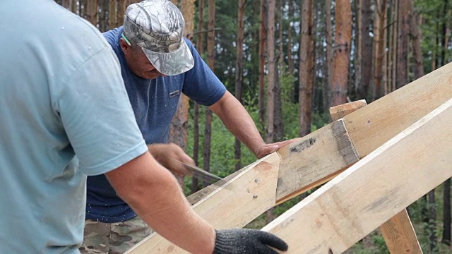 屋顶工人在屋顶上工作。建筑工人用锤子锤钉子。视频素材