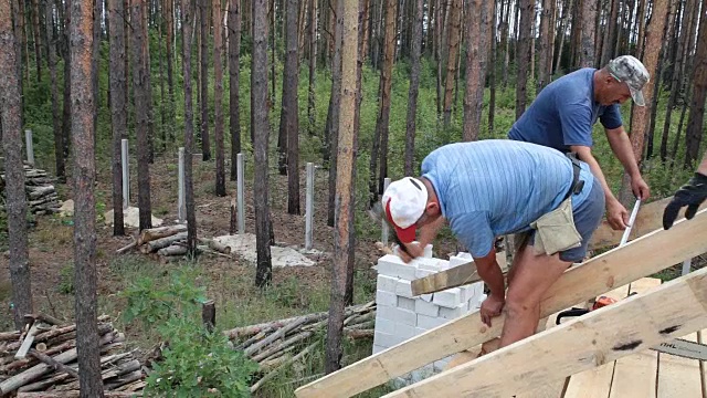 屋顶工人在屋顶上工作。建筑工人用锤子锤钉子。视频素材