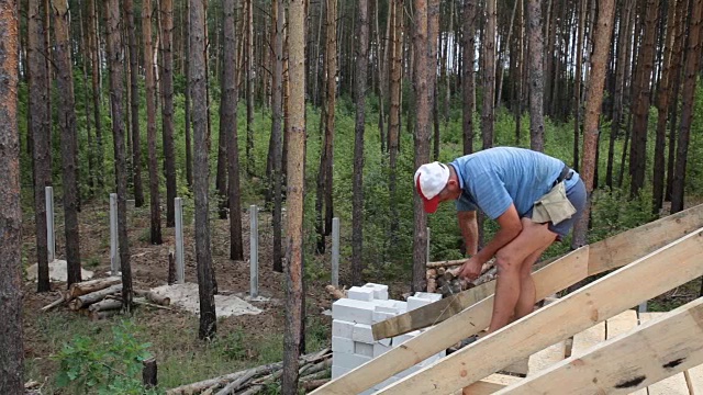 屋顶工人在屋顶上工作。建筑工人用锤子锤钉子。视频下载