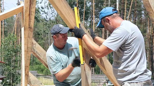 屋顶工人在屋顶上工作。建筑工人用锤子锤钉子。视频下载