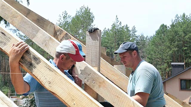 屋顶工人在屋顶上工作。建筑工人用锤子锤钉子。视频下载