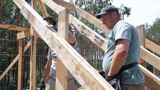 屋顶工人在屋顶上工作。建筑工人用锤子锤钉子。视频下载