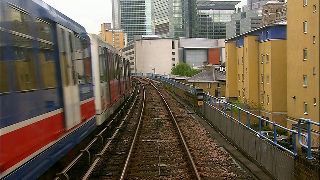 港区轻轨(DLR)列车在轨道上通过/离开车站/伦敦视频素材