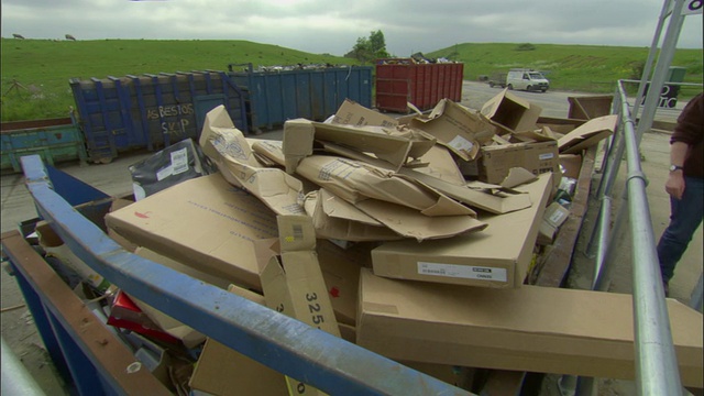 英国牛津郡阿德利，一名正在把纸板箱放入回收箱的妇女视频素材