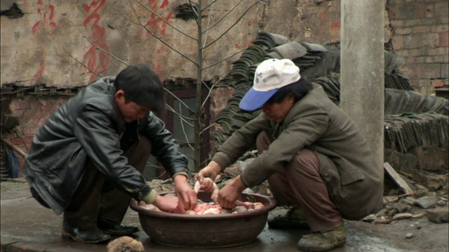 两个蹲着的男人在一个碗里处理动物的内脏/中国贵阳视频素材