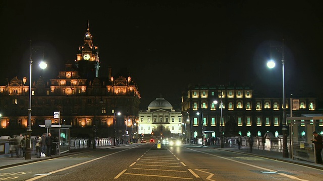 英国苏格兰爱丁堡的T/L, WS，街道上的夜间交通，背景是总登记大厦和巴尔莫勒尔酒店视频素材