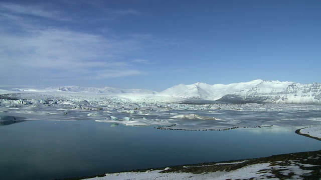 冰岛Vatnajokull冰原和湖泊，在冰川底部包含小冰山和小群体的海豹，雪覆盖的山脉背景/冰岛视频素材