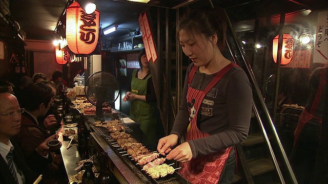 在东京，日本的餐厅里，女人在煮烤肉视频素材