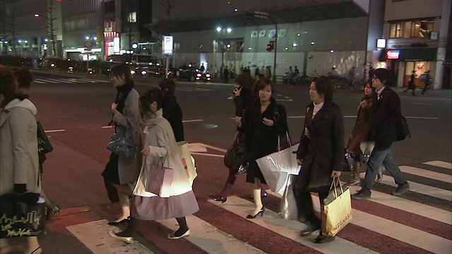 晚上，日本东京新宿，妇女们拿着购物袋过马路视频素材