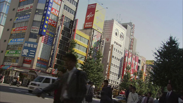 横过秋叶原街道的行人，背景是交通和电子产品商店/东京视频素材