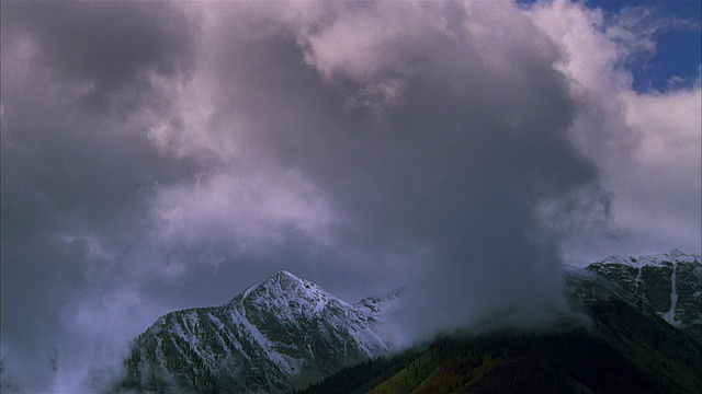 时间间隔宽拍摄低，浓密的云吹过积雪覆盖的山峰落基山脉/黄石国家公园视频素材