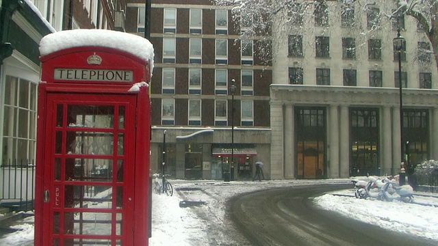 伦敦电话亭被雪覆盖，大型建筑在背景中，英国伦敦视频素材