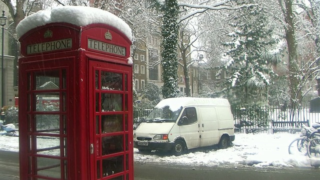 伦敦电话亭被雪覆盖，大型建筑在背景中，英国伦敦视频素材