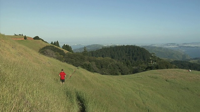 一对夫妇在起伏的山丘上慢跑，一个人在附近放风筝，Tamalpais山，美国加利福尼亚州视频素材