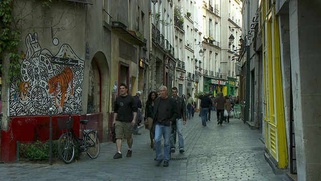 法国巴黎，一大群行人走在玫瑰街(Rue des Rosiers)街角的传统熟食店视频下载