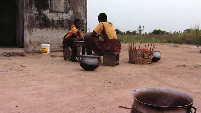 加纳Tamale，孩子们坐在棚屋外吃饭视频素材