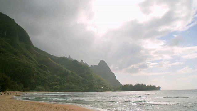 T/L WS吉林海滩的海洋和山丘，两个人走在沙地上/考艾岛，夏威夷，美国视频素材