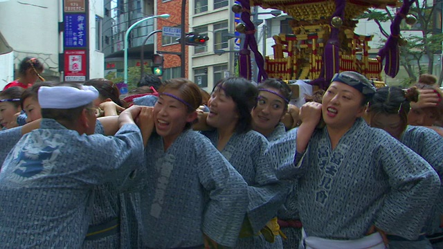 在秋天的节日里，日本东京涩谷，身着日本传统服饰的妇女手持便携式神龛跳舞和吟诵视频素材