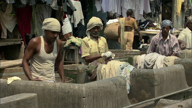 在印度马哈拉施特拉邦孟买，世界上最大的户外洗衣店Dhobi Ghat，工人们在石头上鞭打湿衣服视频素材