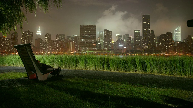 日落时分，美国纽约布鲁克林，坐在长椅上用手机拍摄城市景观的人视频素材