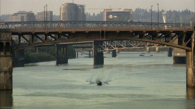 美国俄勒冈州波特兰市，高速驶过河流，背景中桥梁和建筑物上的交通视频素材