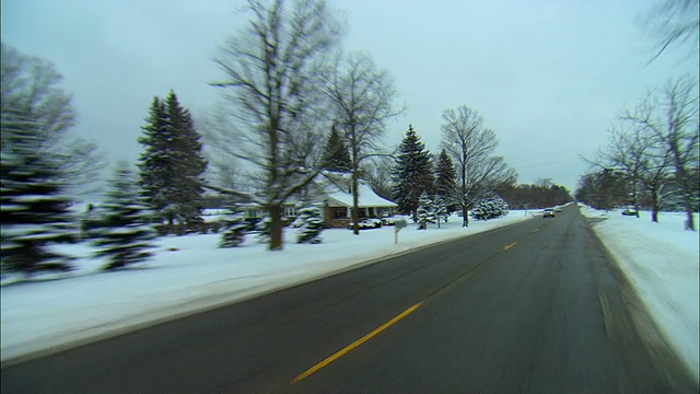 在美国密歇根州米尔福德的大雪覆盖的乡村公路上行驶视频素材