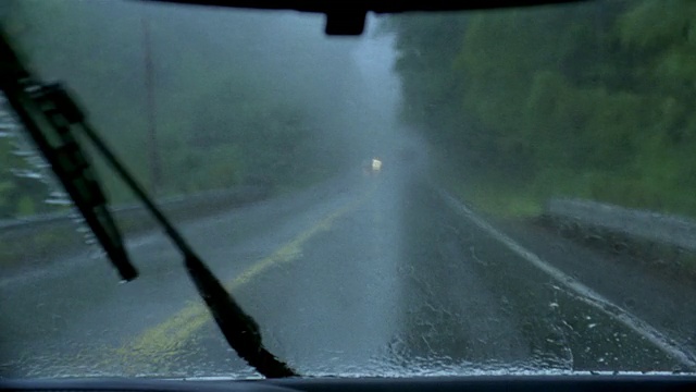 中镜头的汽车视角驾驶在下雨的公路/挡风玻璃雨刷擦雨视频素材