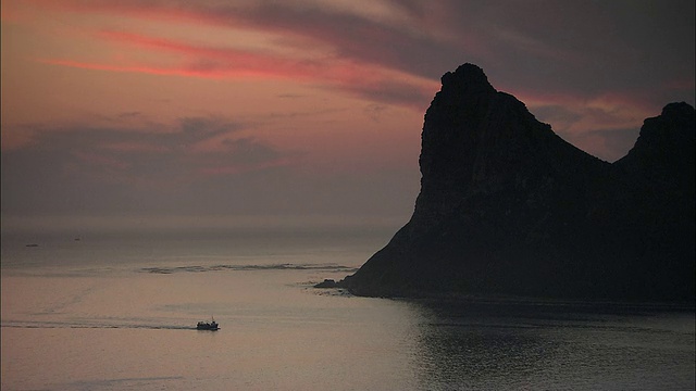 日落时分，在南非西开普半岛/开普镇的海面上驶向海岸的渔船视频素材