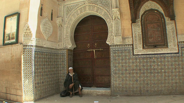 一名男子坐在摩洛哥非斯Moulay Idriss清真寺的门阶上视频素材