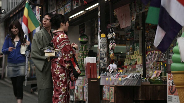 在日本京都东山洼地区礼品店前拥挤的旅游街道上，身着传统服饰的年轻男女视频素材