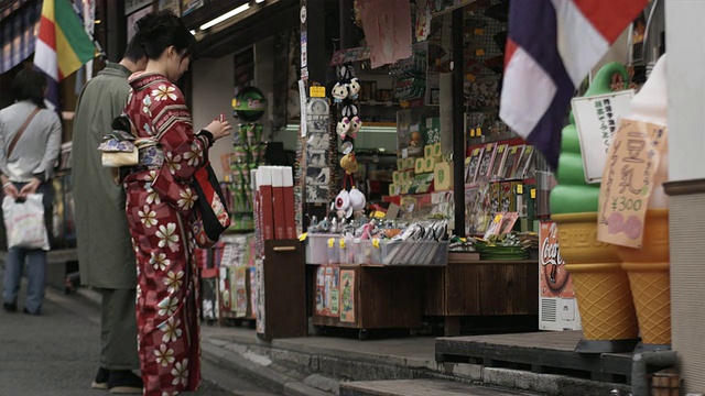 身着传统服饰的年轻男女站在日本京都东山町旅游街道礼品店前视频素材