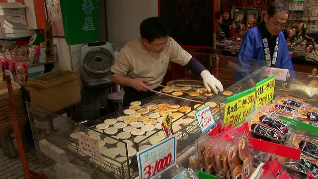 东京Nakamise街步行街，煎饼摊贩正在烤饼视频素材