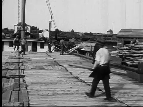 1927年，加拿大安大略省，蒙太奇公司(MONTAGE)潘哈门女士在木材场外工作，将木板车上的木板卸到货船和货车上视频素材