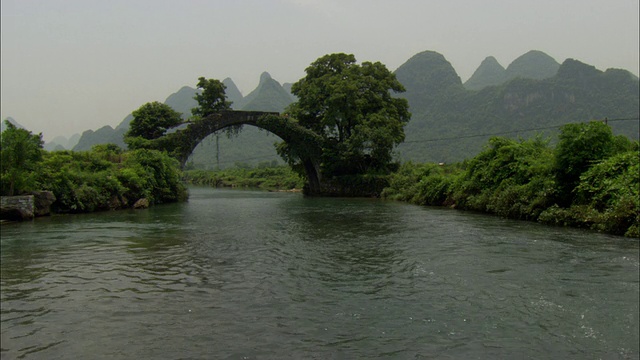 在中国广西壮族自治区桂林，以拱桥和山脉为背景的泛江视频素材