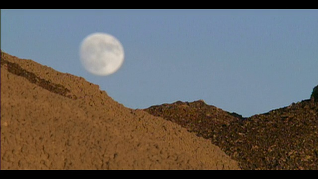 新墨西哥州Bisti/De-Na-Zin荒野地区，一轮满月刚刚升起，低垂在地平线上视频素材